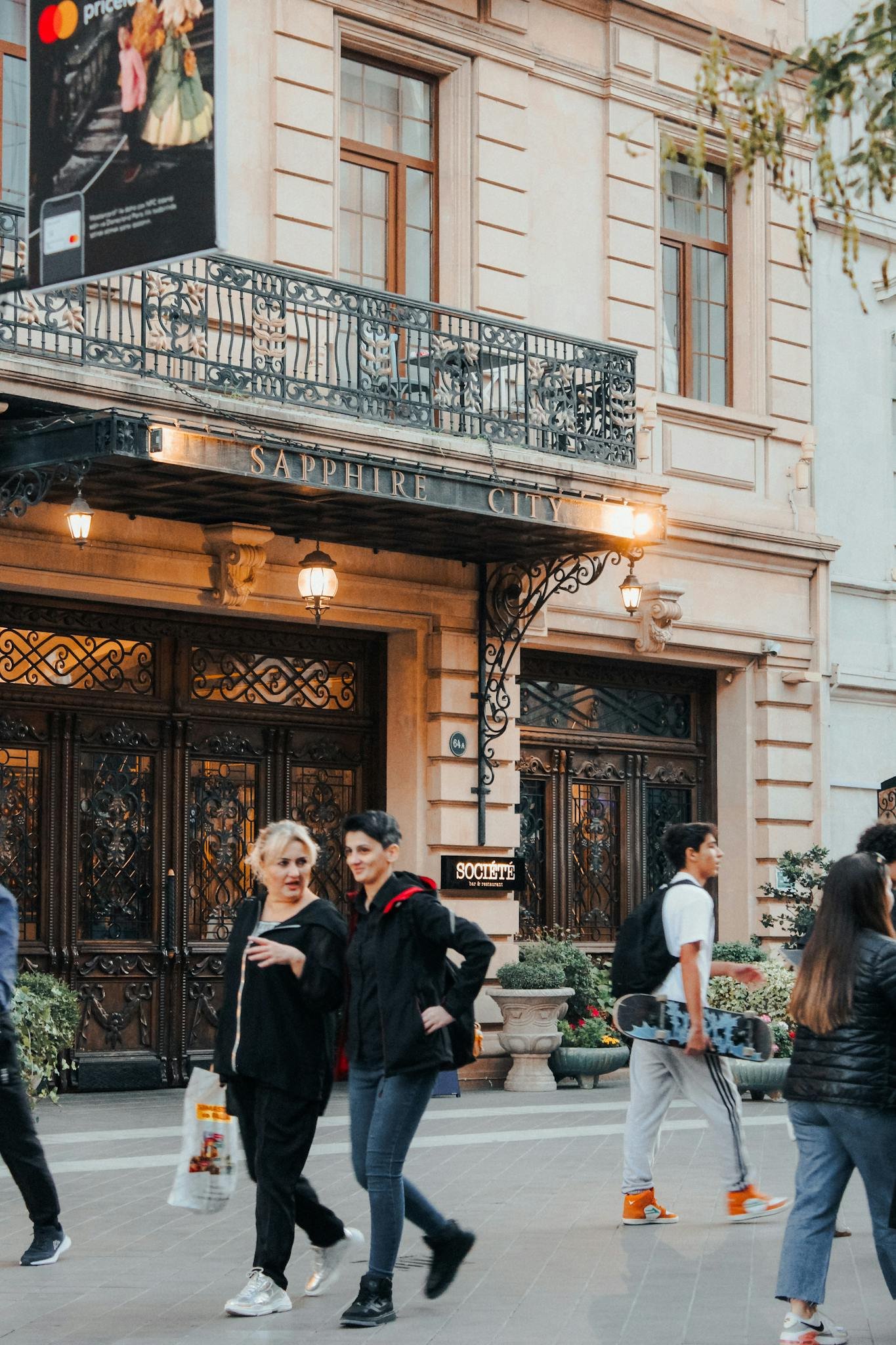 People walking outside the Sapphire City Hotel, capturing urban life and architecture.