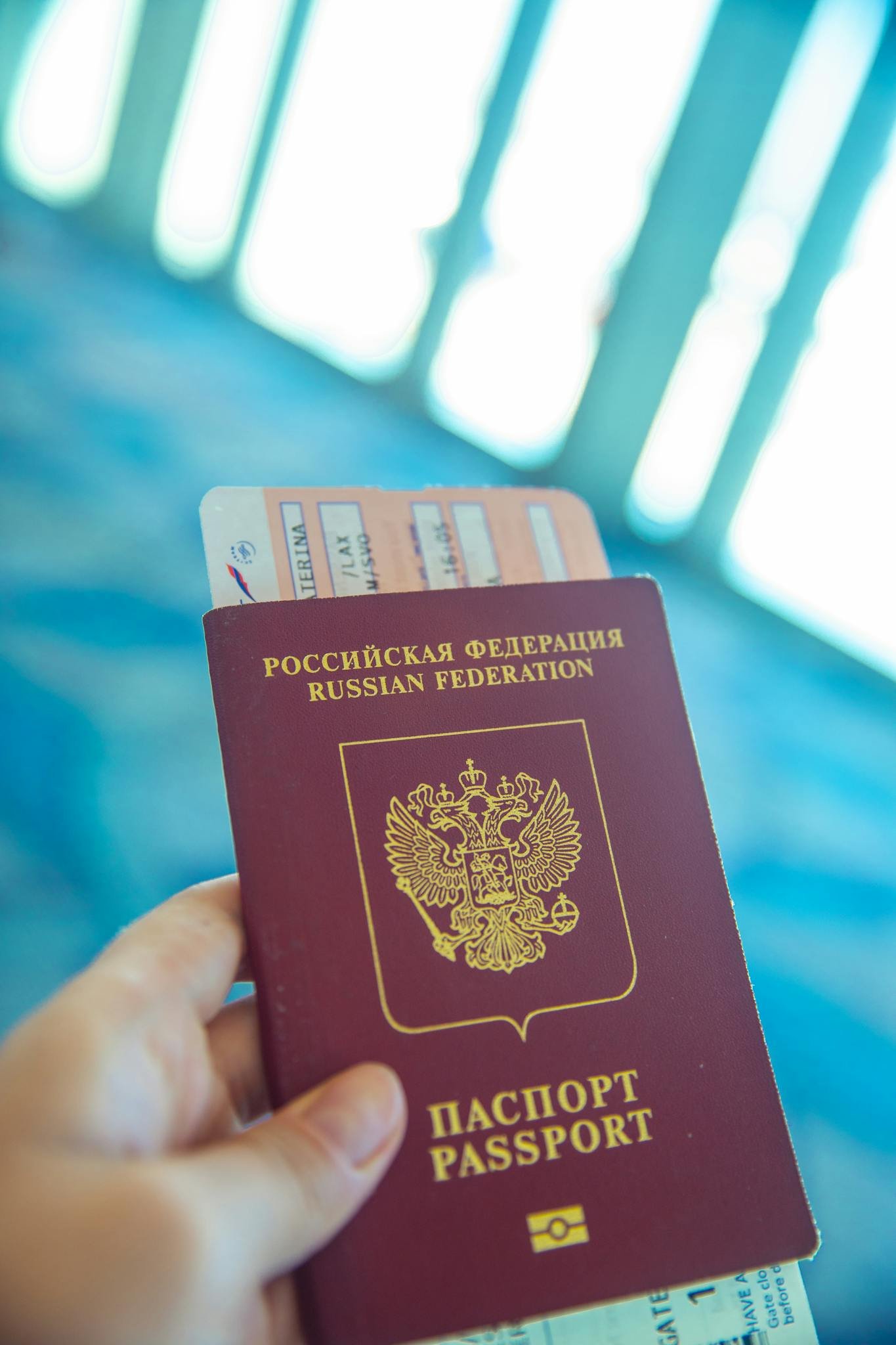 Russian passport held in hand with boarding pass peeking out, ready for travel.